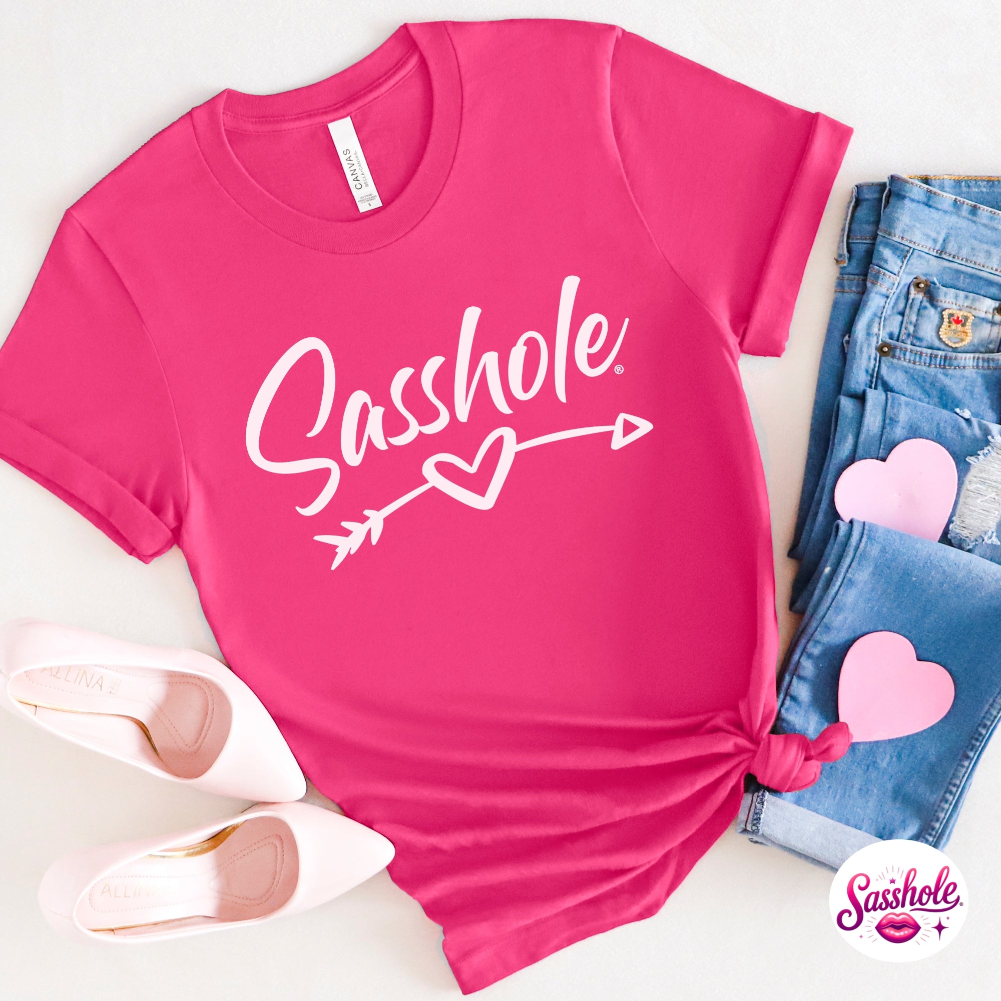 Image of Pink t-shirt with 'Sashole' text and heart design, paired with jeans and shoes on a white background.