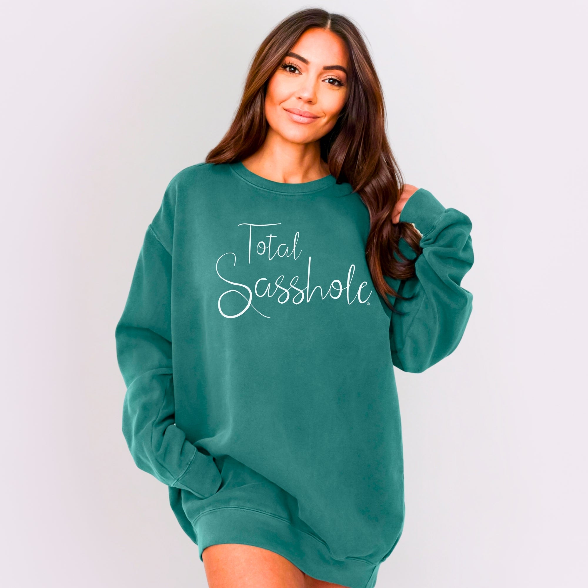 Person wearing a teal sweatshirt with 'Total Sasshole' text on a plain background