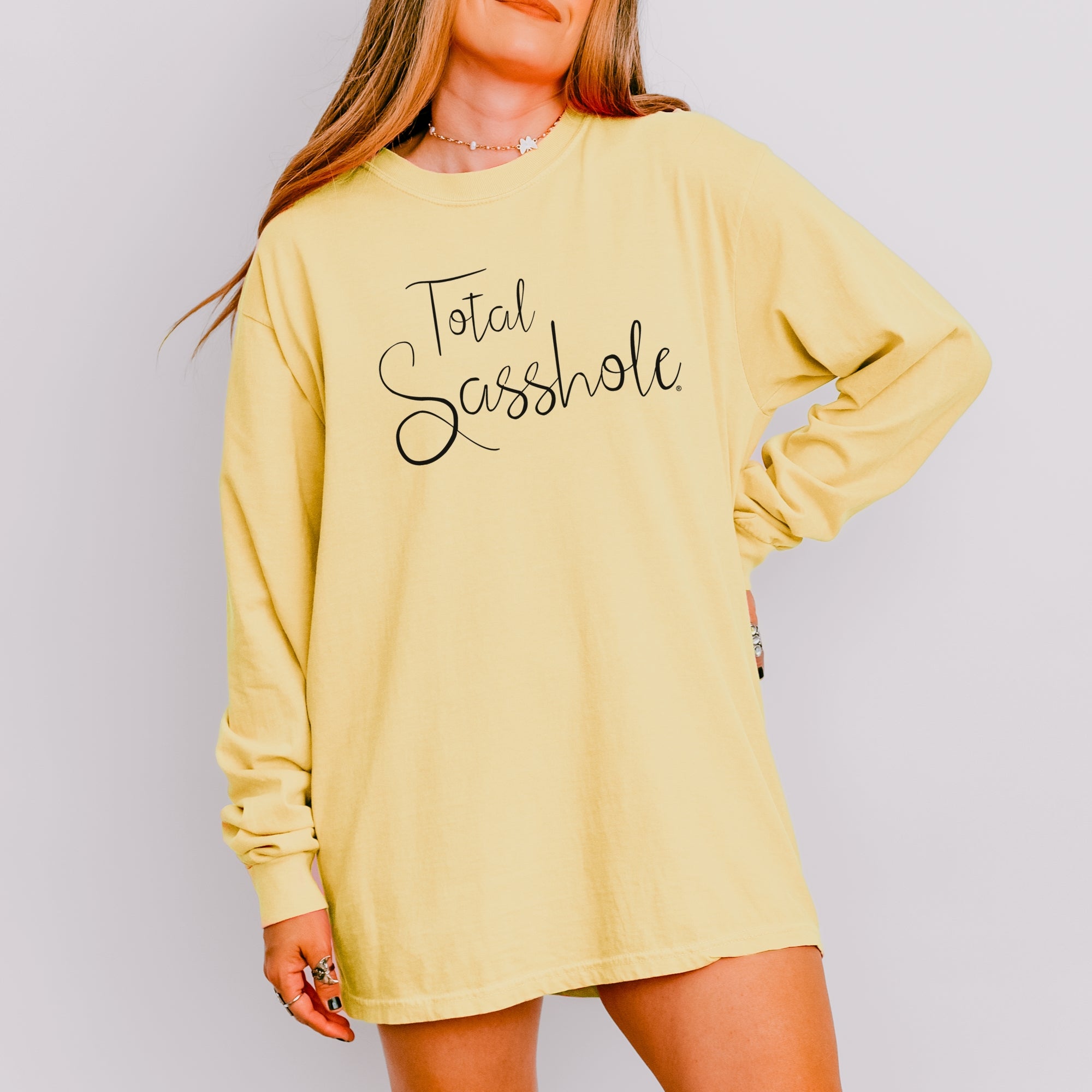 Image of Woman wearing a Butter long-sleeve t-shirt with 'Total Sasshole' text on a plain background