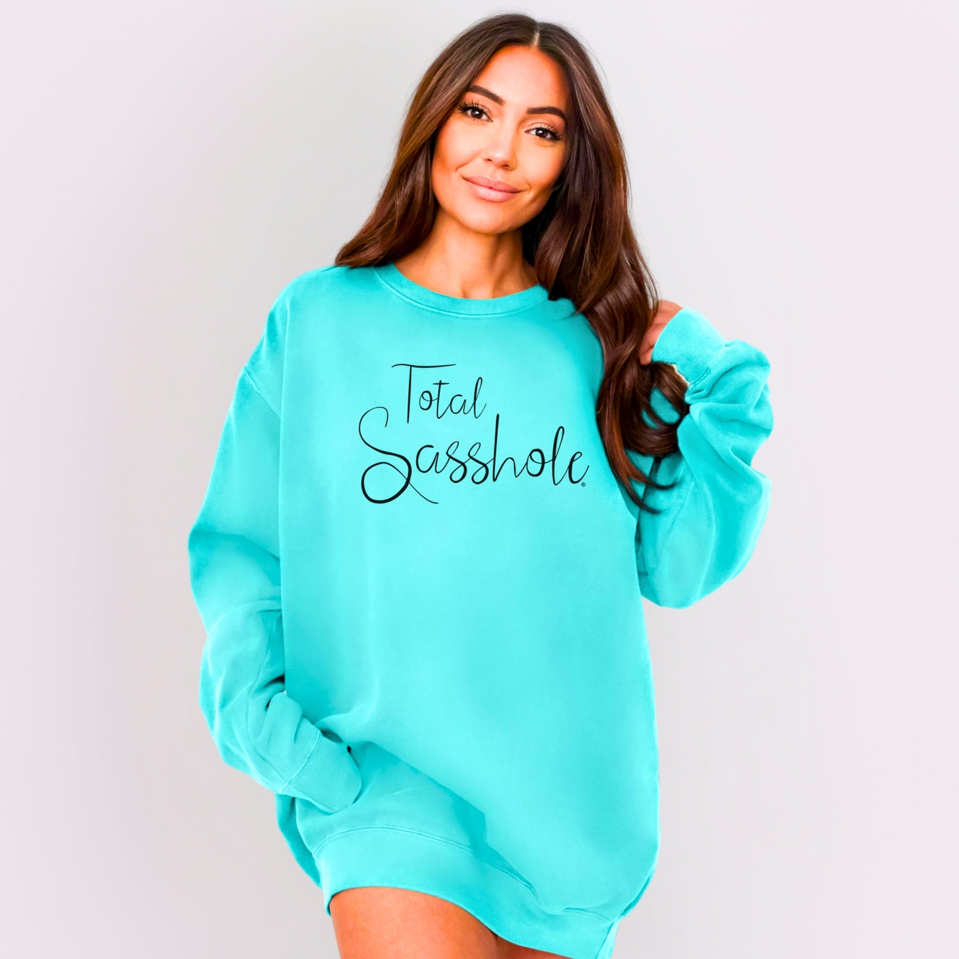 Woman wearing a turquoise sweatshirt with 'Total Sasshole' text on a plain background