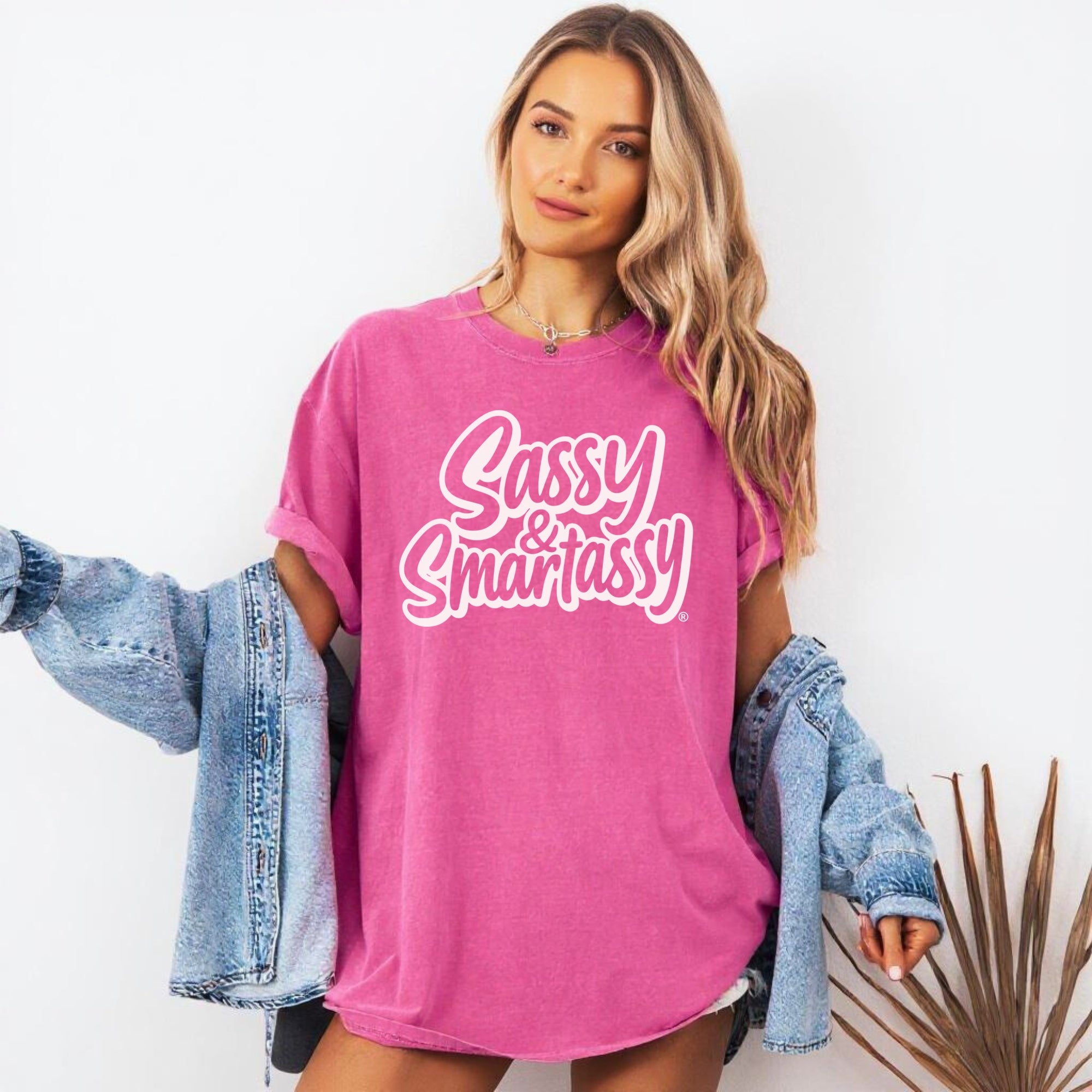 Image of Woman wearing a pink t-shirt with 'Sassy & Smartassy' text, holding denim jackets.