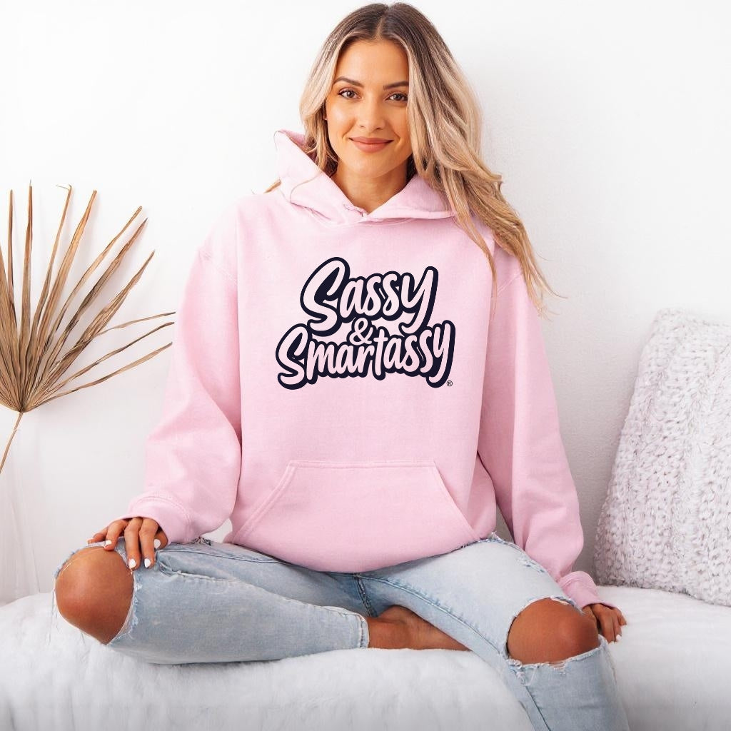 Image of Woman wearing a light pink hoodie with 'Sassy & Smartassy' text, sitting on a couch.