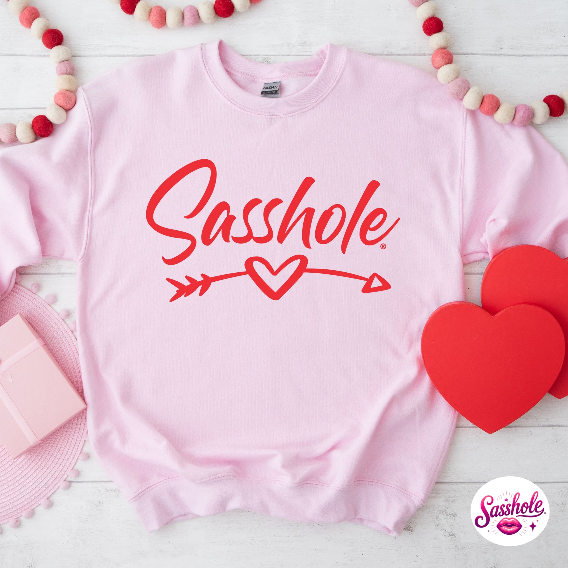 Pink sweatshirt with 'Sasshole' text and heart design on a white background