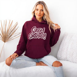 Image of Woman wearing a maroon hoodie with 'Sassy & Smartassy' text, sitting on a white couch.