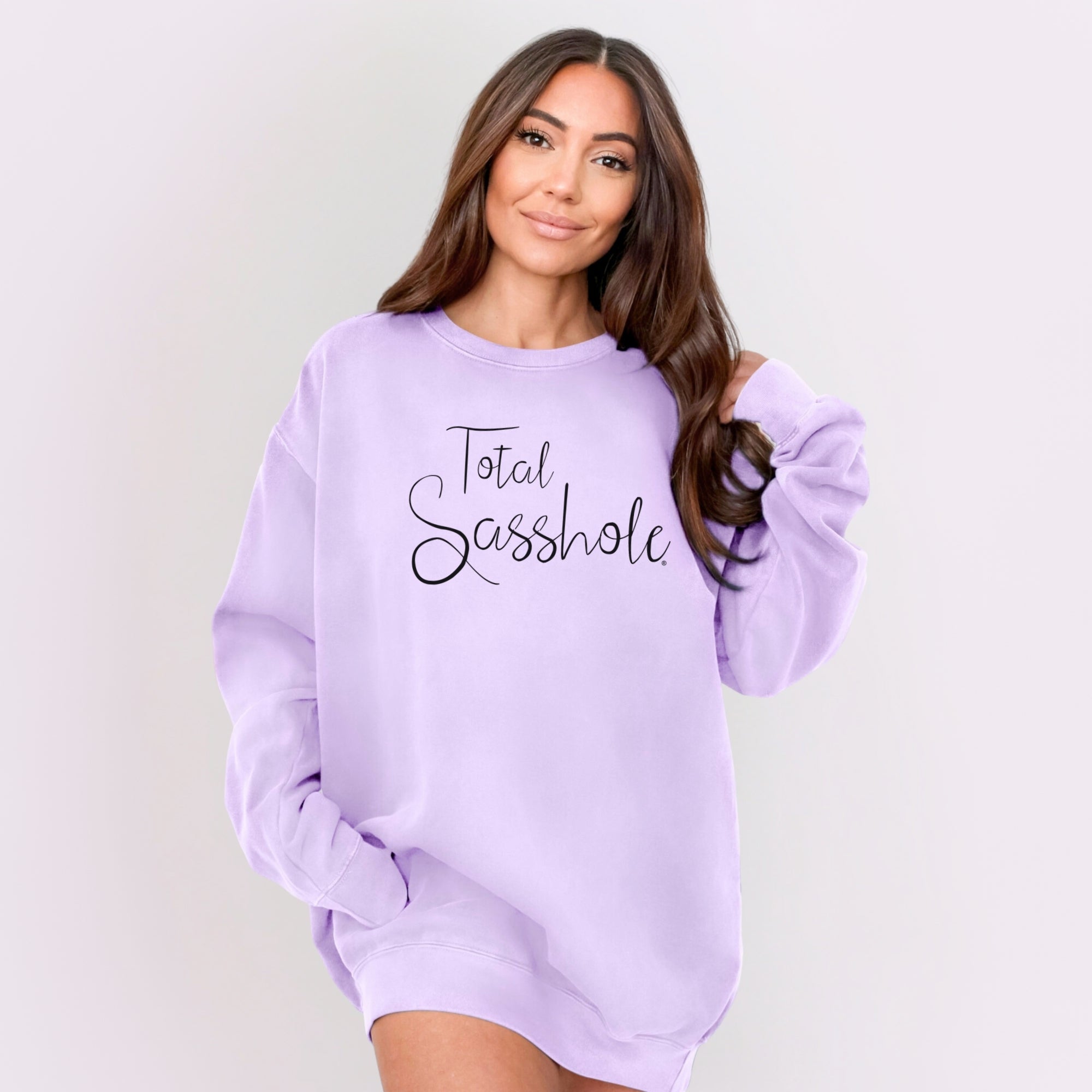 Woman wearing a lavender sweatshirt with 'Total Sasshole' text on a plain background