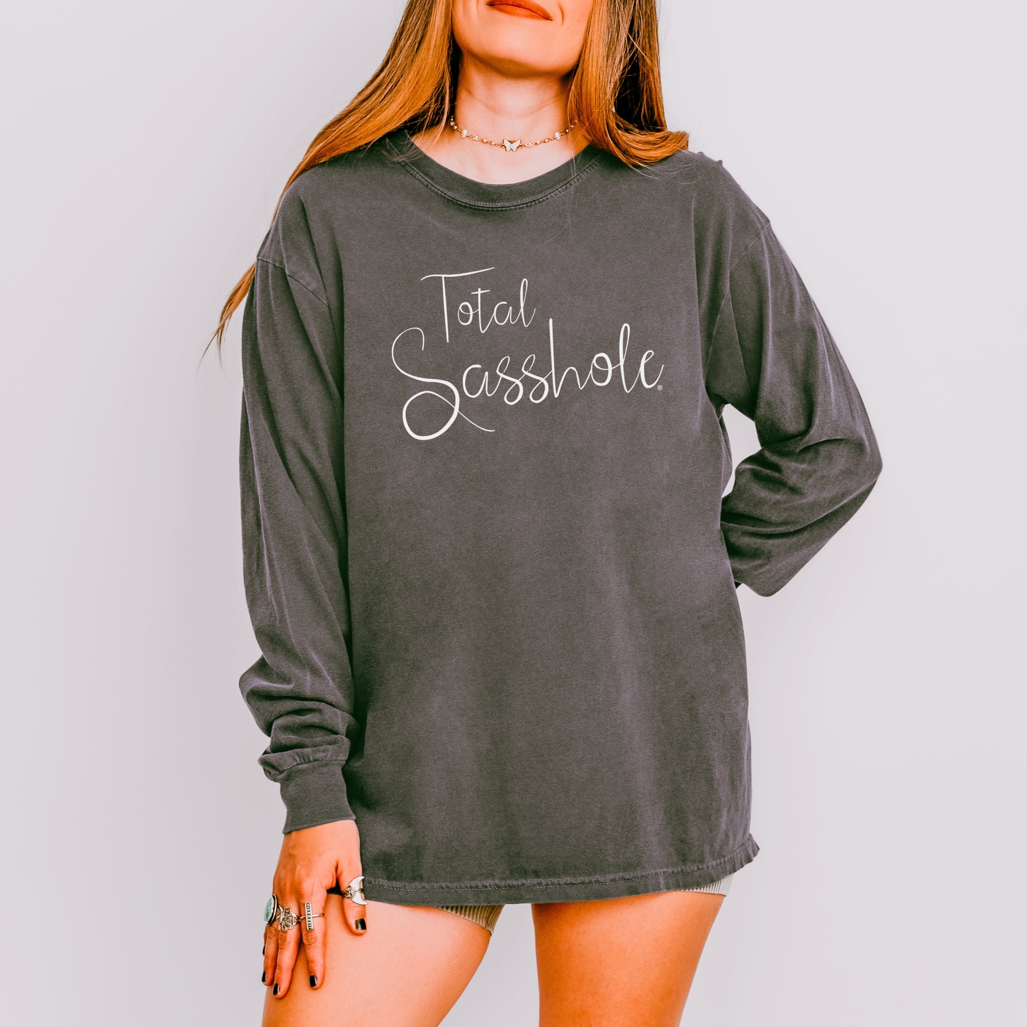 Image of Woman wearing a pepper color long-sleeve shirt with 'Total Sasshole' text on a plain background
