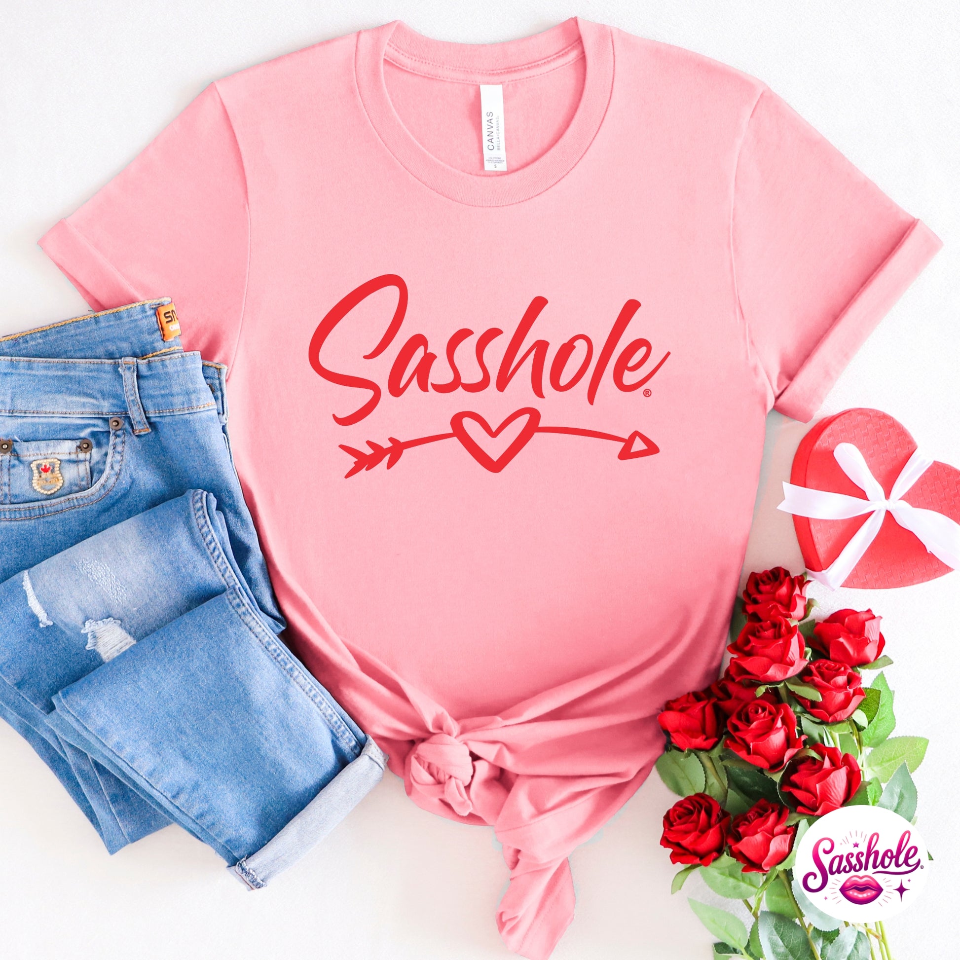 Pink t-shirt with 'Sasshole' graphic, blue jeans, and red roses on a white background