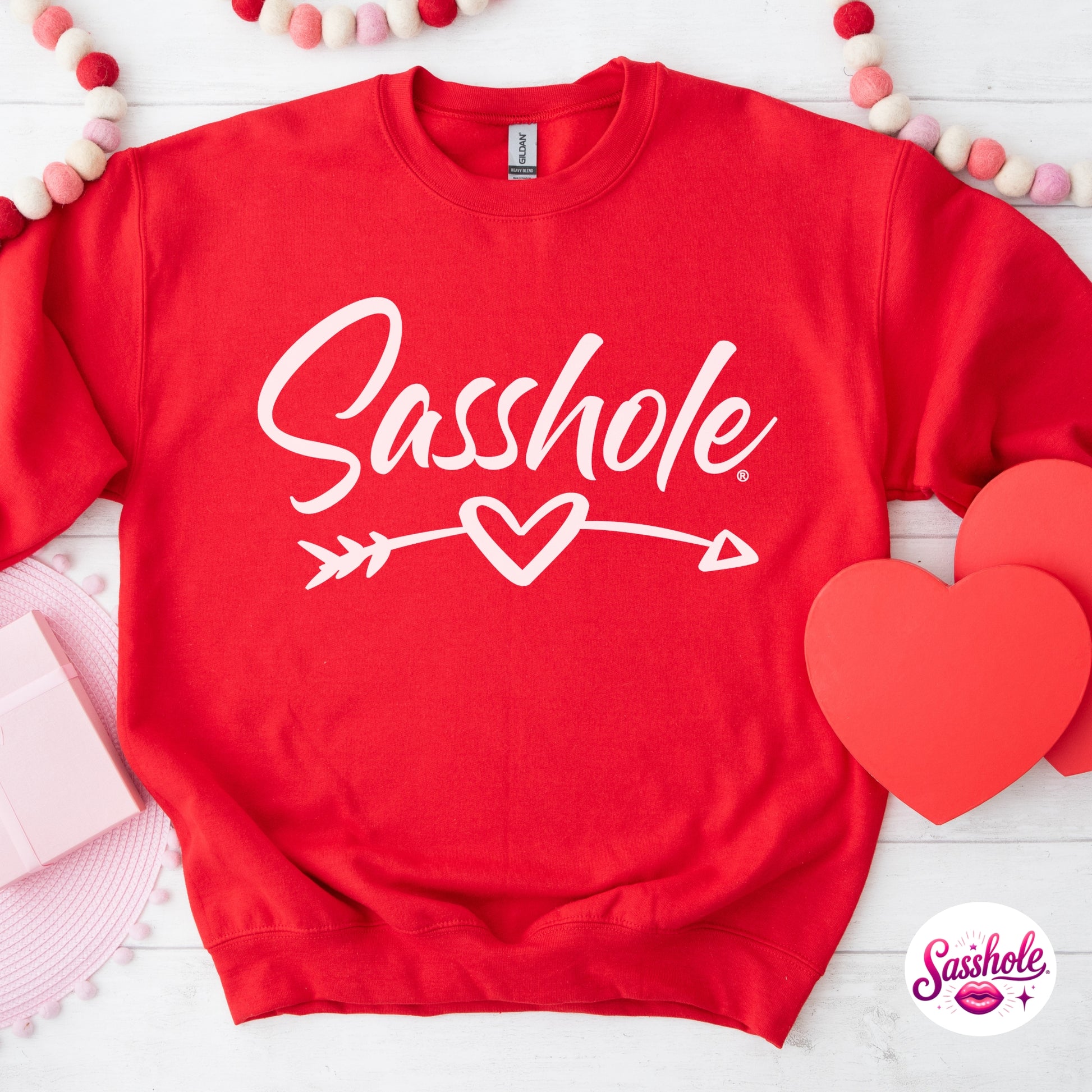 Red sweatshirt with 'Sasshole' text and heart design on a white background