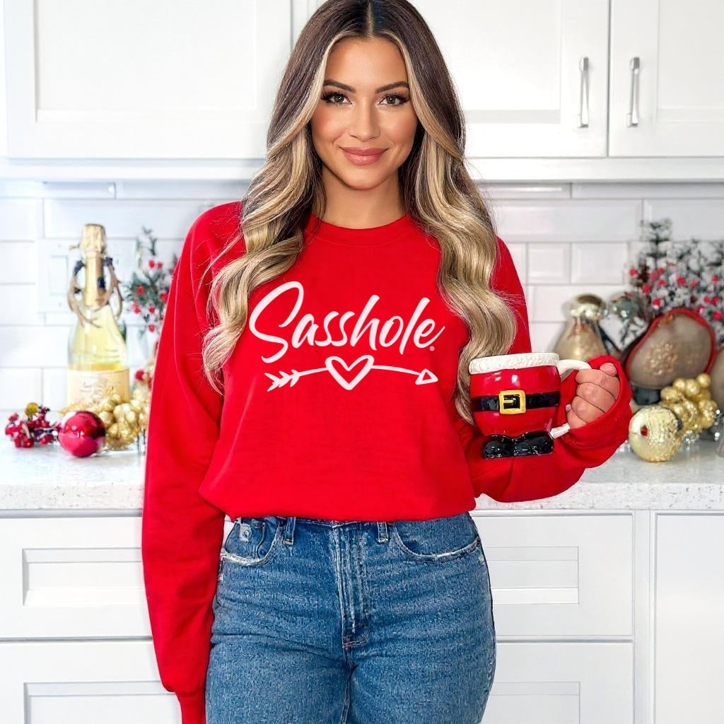 Person wearing a red sweatshirt with 'Sasshole' text, holding a mug in a kitchen setting.