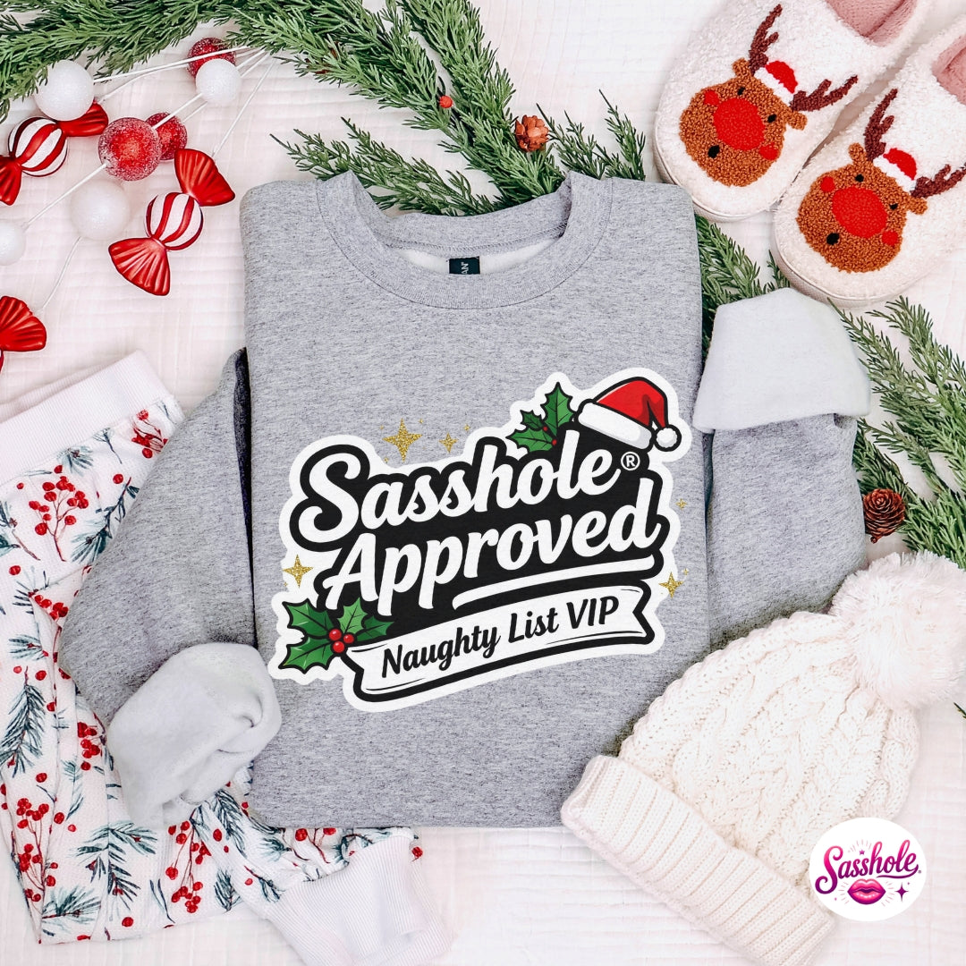 Gray sweatshirt with 'Sasshole Approved Naughty List VIP' text, surrounded by Christmas decorations.