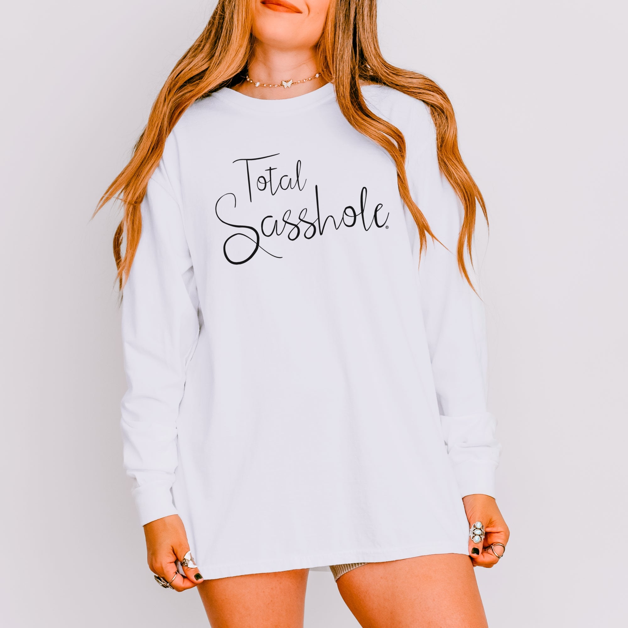 Image of Woman wearing a white long sleeve t-shirt with 'Total Sasshole' text on a plain background