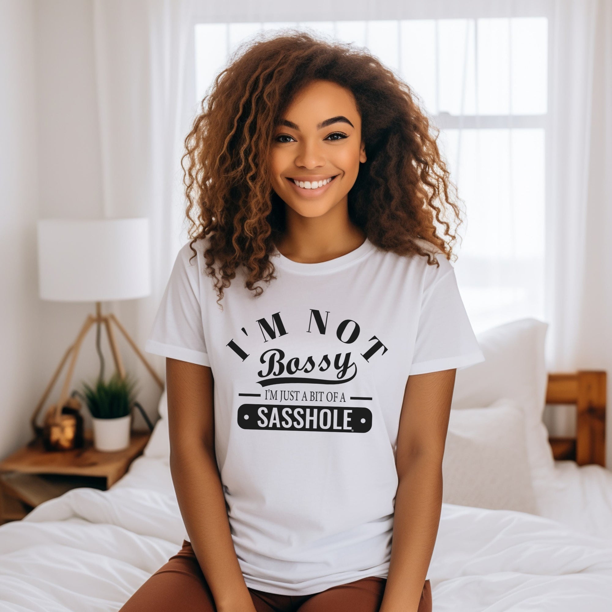 Woman wearing a white t-shirt with humorous text in a bedroom setting