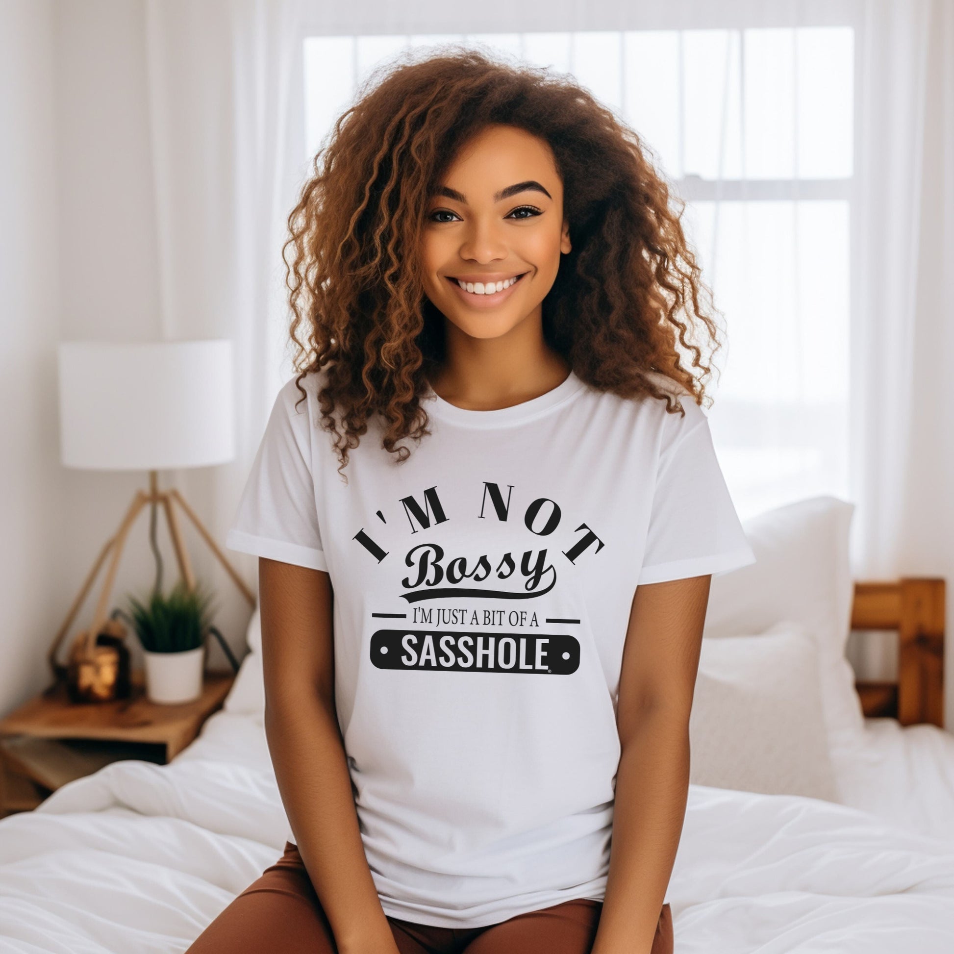 Woman wearing a white t-shirt with humorous text in a bedroom setting