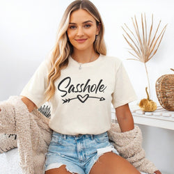 Image of Woman wearing a natural t-shirt with 'Sasshole' text, sitting in a cozy room