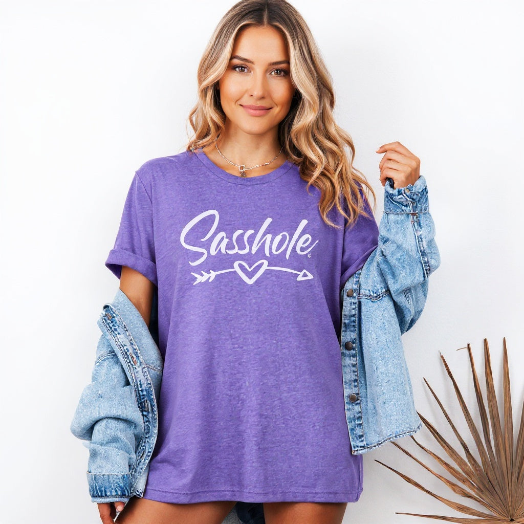Image of Woman wearing a purple t-shirt with 'Sasshole' text, holding a denim jacket on a white background.